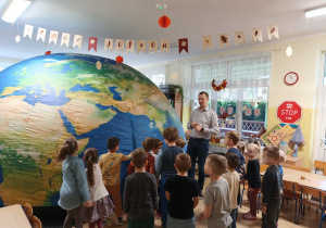 przedszkolaki stoją obok rozłożonego planetarium, edukator tłumaczy dzieciom, co będą oglądały
