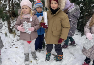grupa dzieci w przedszkolnym ogrodzie z odnalezionymi prezentami w dłoniach