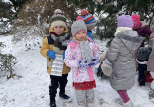 grupa dzieci w przedszkolnym ogrodzie z odnalezionymi prezentami w dłoniach