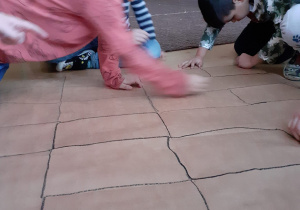 dzieci na karcie zabawy kreślą czarną pastelą prostokąty (po linii zgięcia papieru)