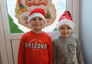 dwoje dzieci pozuje do zdjęcia w mikołajkowych czapkach