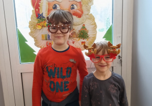dwoje dzieci pozuje do zdjęcia w mikołajkowych okularach