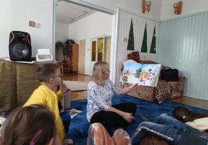 pani bibliotekarka czyta dzieciom świąteczne opowiadanie , obok siedzą dzieci