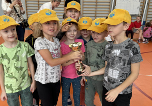 grupa dzieci - sportowców pozuje do zdjęcia z pucharem w rękach