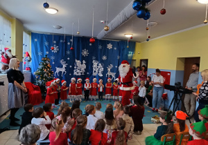 grupa dzieci ubranych odświętnie zgromadzona w szatni wita Mikołaja