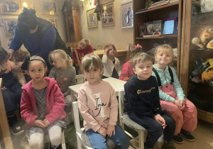 dzieci siedzą przy stolikach w Baśniowej Kawiarence , obok pani woźna