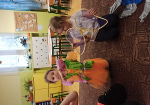 dziewczynki siedzą na dywanie i oglą dają karnawałowe przebrania (sukienki księżniczek)