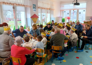 Zaproszeni na Dzień Babci i Dziadka goście uczestniczą z wnuczętami w okolicznościowym poczęstunku w klasie