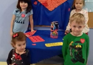 czworo dzieci stoi na tle czerwonego dużego serca