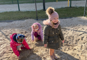 troje dzieci bawi się w piasku