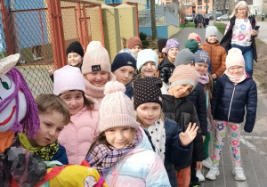 Grupa dzieci przygotowuje się do wyjścia na imprezę "pożegnania zimy", z przodu marzanna, z tyłu pani dyrektor