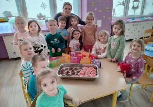 nauczycielka i dzieci pozują do zdjęcia, na stoliku przygotowane przez nich muffinki