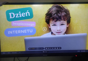 slajd na tablicy multimedalnej - napis: dzień bezpiecznego internetu i zdjęcie dziecka z laptopem