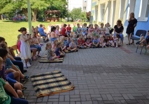 społeczność przedszkolna zebrana na tarasie (dzieci, pracownicy), będą słuchać bajek czytanych przez p. dyrektor i nauczycielki