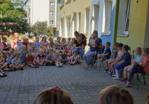 społeczność przedszkolna zebrana na tarasie (dzieci, pracownicy), słuchają bajek czytanych przez p. dyrektor