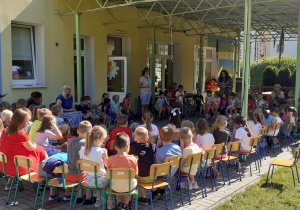 społeczność przedszkolna zebrana na tarasie (dzieci, pracownicy), będą słuchać bajek czytanych przez p. dyrektor i nauczycielki