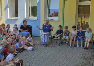 społeczność przedszkolna zebrana na tarasie (dzieci, pracownicy), słuchają bajkę czytaną przez p. dyrektor