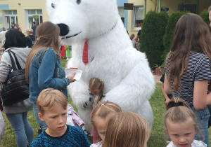 grupa dzieci w przedszkolnym ogrodzie, w tle wielki biały miś