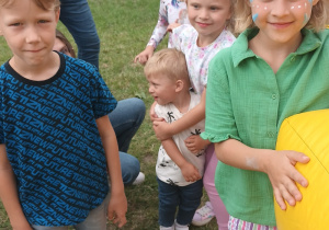 kilkoro dzieci stoi w kolejce do zabawy na dmuchańcu