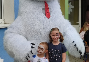 dwoje dzieci pozuje do zdjęcia przy wielkim białym misiu