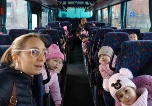 Grupa dzieci i nauczycielka w autobusie. Jadą do kina