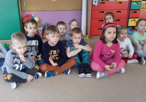 grupa dzieci siedzi na dywanie i ogląda film edukacyjny