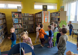 dzieci w bibliotece, chodzą między regałami z książkami