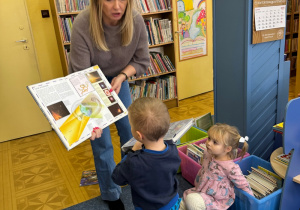 dzieci w bibliotece, pani bibliotekarka pokazuje im ksiażeczki