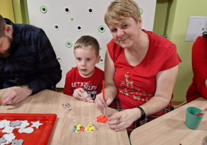 Mama z synem pozują do zdjęcia podczas przygotowania ozdób choinkowych.