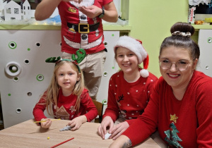Rodzina pozuje do zdjęcia podczas przygotowania ozdób choinkowych.