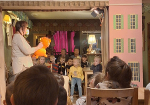 Aktorka występuje na scenie. Trzyma kukiełkę przedstawiającą lwa.