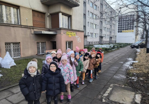 Grupa dzieci pozuje do zdjęcia przed budynkiem "Baśniowej Kawiarenki".