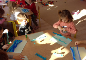 dzieci wykonują pracę plastyczną z bibuły i kółek origami
