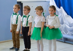 Dwie dziewczynki i dwóch chłopców stoją na scenie podczas występu.