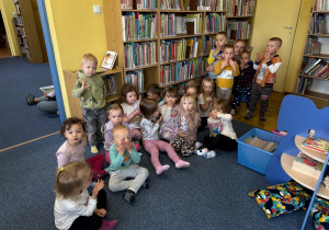 grupa dzieci i pani bibliotekarka w bibliotece pozują do wspólnego zdjęcia