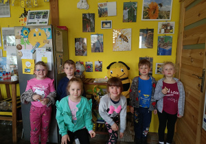 grupa dzieci w pomoieszczeniu w pasiece, dzieci stoją przy wielkiej , ręcznie wykonanej pszczole, pozują do zdjęcia