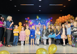grupa przedszkolaków i dorośli na scenie pozują do zdjęcia na zakończenie wydarzenia