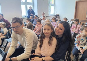 dziewczynka występująca siedzi z rodzicami w miejscu publiczności