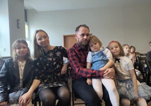 występujące dzieci z rodzicami siedzą w miejscu publiczności