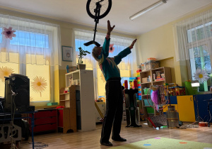 artysta cyrkowy, ubrany charakterystycznie prezentuje cyrkową sztuczkę