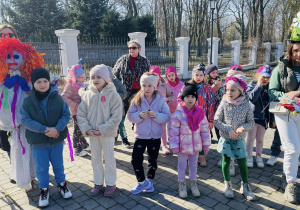 grupa dzieci i nauczycielki na dziedzińcu MOK, obok widać marzannę