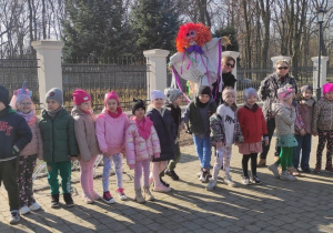 grupa dzieci i nauczycielki na dziedzińcu MOK, nauczycielka trzyma marzannę