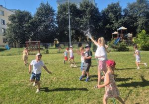 dzieci w ogrodzie przedszkolnym polewają się wodą