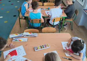 dzieci przy stolikach kolorują obrazki owoców