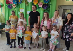 nagrodzeni w konkursie pozują do wspólnego zdjęcia (dzieci trzymajądyplomy i nagrody, za przedszkolakami stoją opiekunowie)