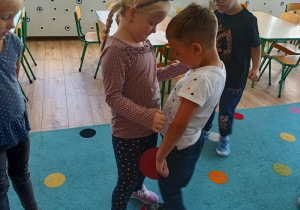 dwoje dzieci w zabawie ruchowej, obok przypatrujący się rówieśnicy