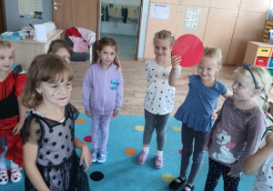 grupa dziewczynek stoi w kole, jedna z nich trzyma w dłoni czerwone koło