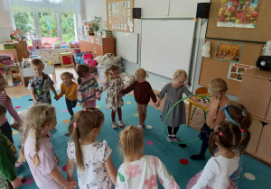 dzieci stoją w kole i biorą udział w zabawie z hula hop
