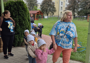 nauczycielka prowadzi najmłodszą grupę do zabaw w ogrodzie