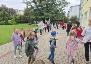 grupa dzieci i ich panie podczas zabawy muzycznej w ogrodzie przedszkolnym